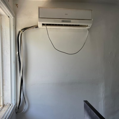 מזגן מותקן על קיר עם כבלים חשמליים גלויים