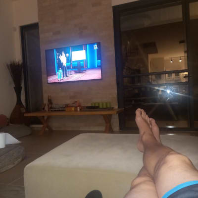 אדם יושב בסלון מול טלוויזיה דולקת