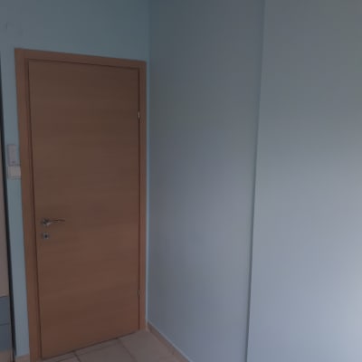 קיר צבוע בצבע כחול בהיר ליד דלת עץ