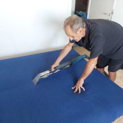 אדם מנקה ספה כחולה עם מכשיר ניקוי