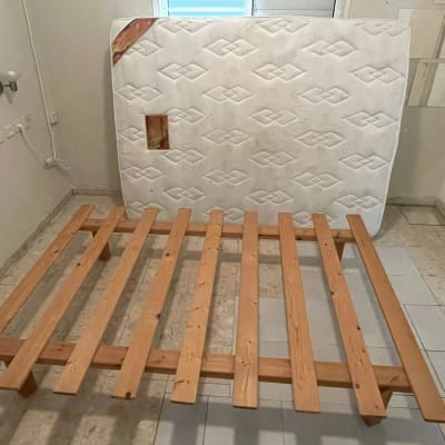 מזרן עומד על הקיר ליד מסגרת מיטה מעץ