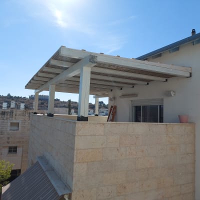 פרגולה מעץ על מרפסת אבן עם עציץ