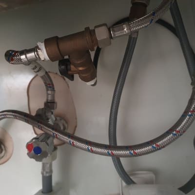 צינורות מתכת מחוברים לברזים מתחת לכיור