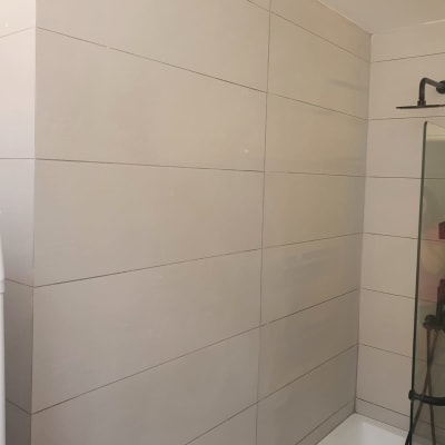 קיר אריחים חדשים בחדר אמבטיה עם מקלחון