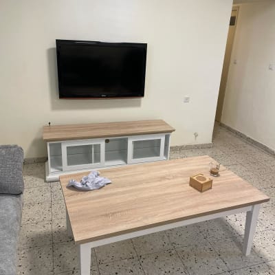 שולחן עץ עם חפצים, טלוויזיה תלויה על הקיר