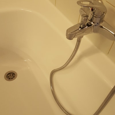 ברז אמבטיה עם צינור מתכת על קיר אריחים