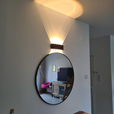 מראה עגולה על קיר עם מנורה מעליה