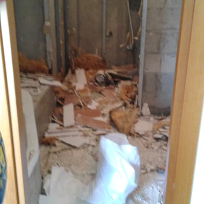 חדר בשיפוץ עם קירות חשופים ופסולת בנייה על הרצפה