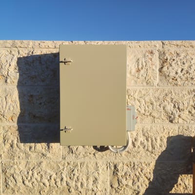 ארון חשמל על קיר אבן עם כבלים