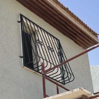 סורג מתכת שחור על חלון קיר חיצוני