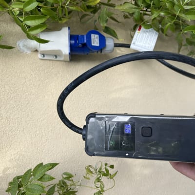 שקע חשמלי עם כבל ומכשיר מדידה ביד חשמלאי