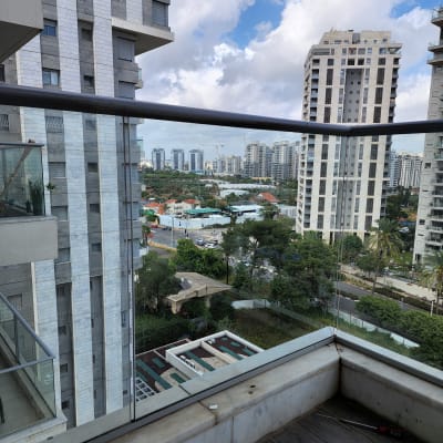 מעקה זכוכית במרפסת עם נוף עירוני ברקע