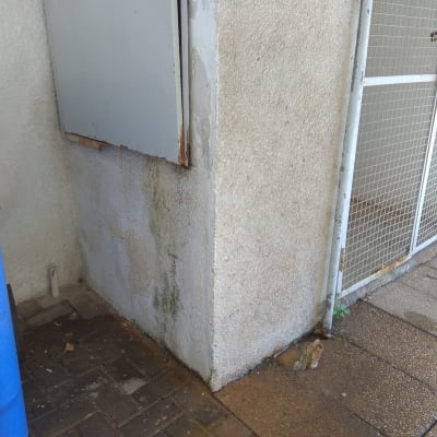 קיר עם סימני רטיבות ודלת מתכת פתוחה