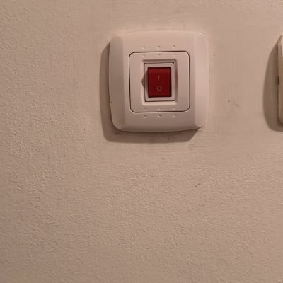 מתג חשמלי עם כפתור אדום על קיר