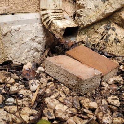 מרזב מתכת עם מים נוזלים על אבנים