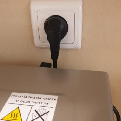 תקע שחור מחובר לשקע חשמלי בקיר