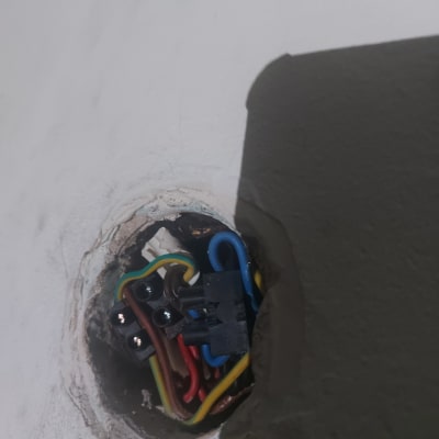 חוטי חשמל צבעוניים מחוברים לקופסת חיבורים בקיר