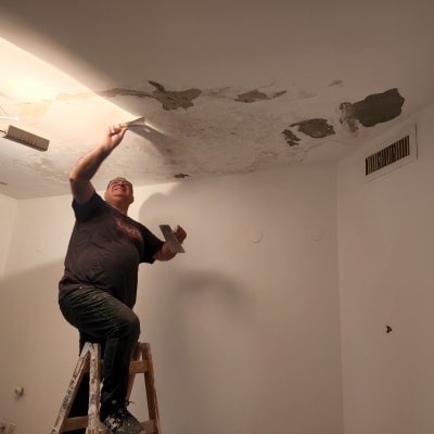 אדם על סולם צובע תקרה עם שפכטל