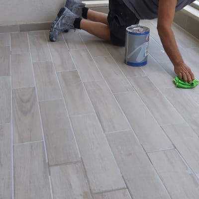 אדם מנקה רצפה עם מטלית ירוקה ודלי צבע