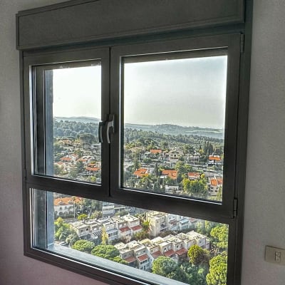 חלון אלומיניום עם נוף עירוני ברקע