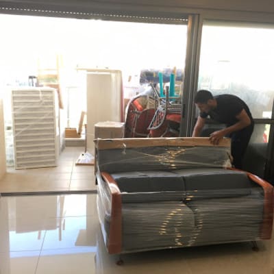 אדם אורז רהיטים עטופים בניילון לקראת מעבר דירה