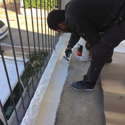 אדם מורח חומר איטום על רצפת מרפסת