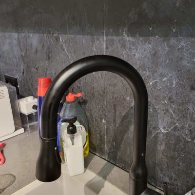 ברז שחור בכיור עם חומרי ניקוי מסביב