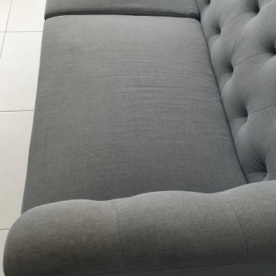 ספה אפורה עם ריפוד כפתורים על רצפה בהירה