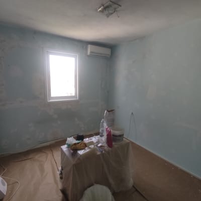 חדר עם קירות צבועים חלקית, שולחן עם ציוד צביעה