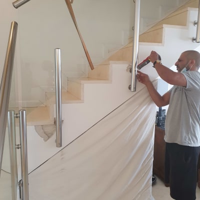 אדם מתקין מעקה מתכת במדרגות עם מקדחה