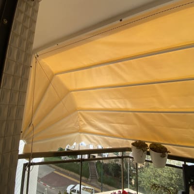 סוכך צהוב מתוח מעל מרפסת עם צמחים תלויים