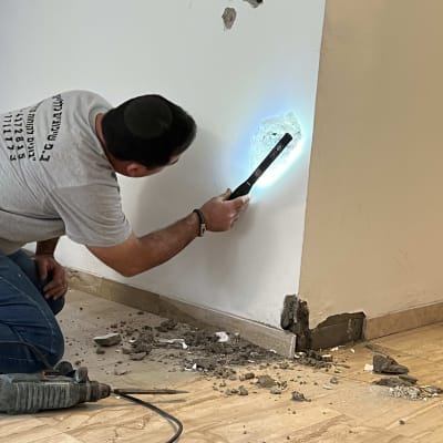 אדם משתמש בכלי עבודה על קיר עם חור