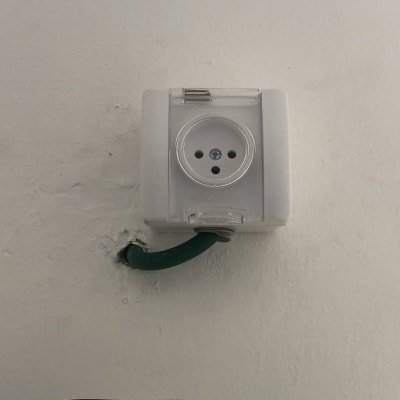 שקע חשמלי עם כבל ירוק בקיר לבן