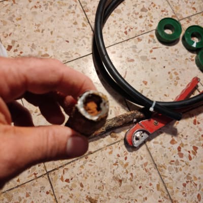 יד מחזיקה צינור חלוד, כלי עבודה וצינורות על הרצפה