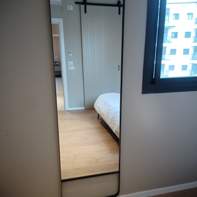 מראה תלויה על קיר עם מסגרת שחורה