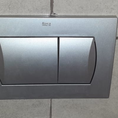 לחצן הדחה כפול כסוף על קיר אריחים