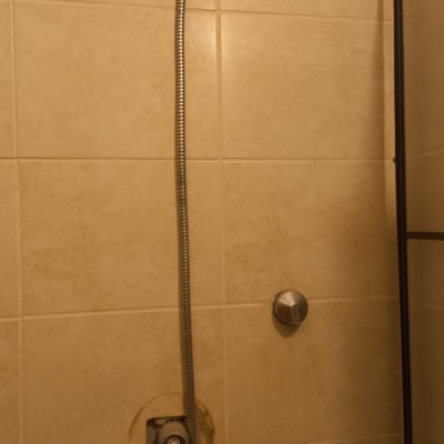 ראש מקלחת עם צינור גמיש על קיר אריחים