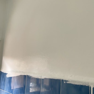 קיר צבוע מעל אריחים כחולים עם פרחים