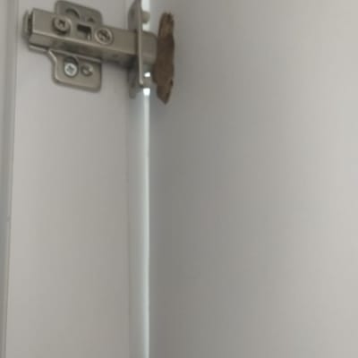 ציר מתכת מותקן על דלת ארון לבנה