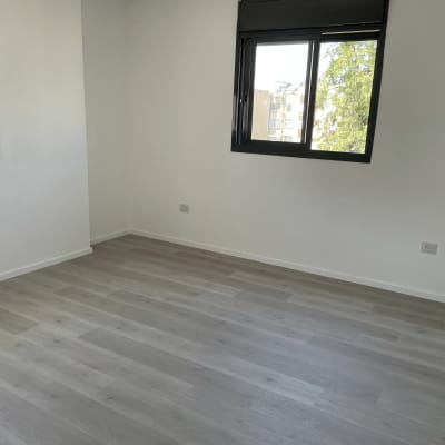 רצפת פרקט עץ בהירה בחדר ריק עם חלונות