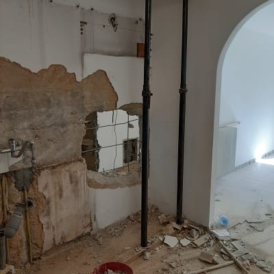 שני עמודי תמיכה, קיר שבור ודלי עם פסולת בנייה