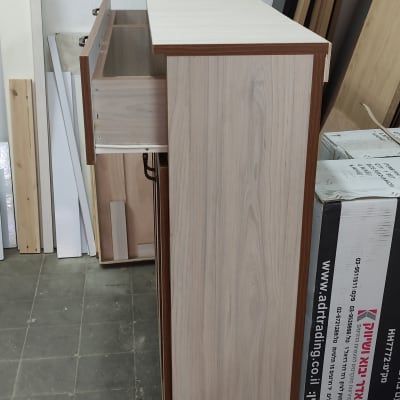 ארון עץ עם מגירה פתוחה וסביבו לוחות עץ