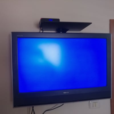 טלוויזיה תלויה על הקיר עם מכשיר עליון