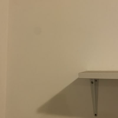 מדף לבן עם תומך מתכת על קיר