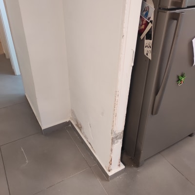 קיר עם סימני תיקון ליד מקרר אפור