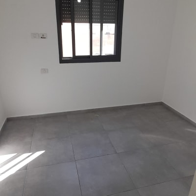 חדר ריק עם קירות לבנים ורצפת אריחים אפורה