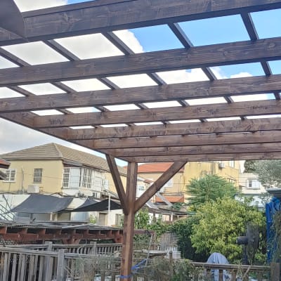 פרגולה מעץ בגינה עם צמחייה מסביב