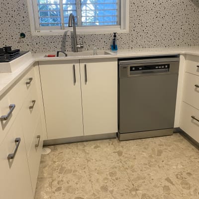 מטבח משופץ עם ארונות לבנים ומדיח כלים אפור