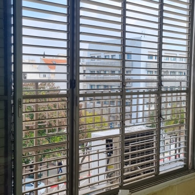 תריסים אופקיים על חלון גדול עם נוף עירוני
