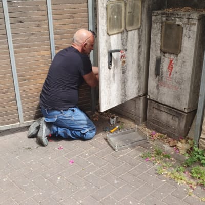 חשמלאי עובד על ארון חשמל פתוח עם כלים